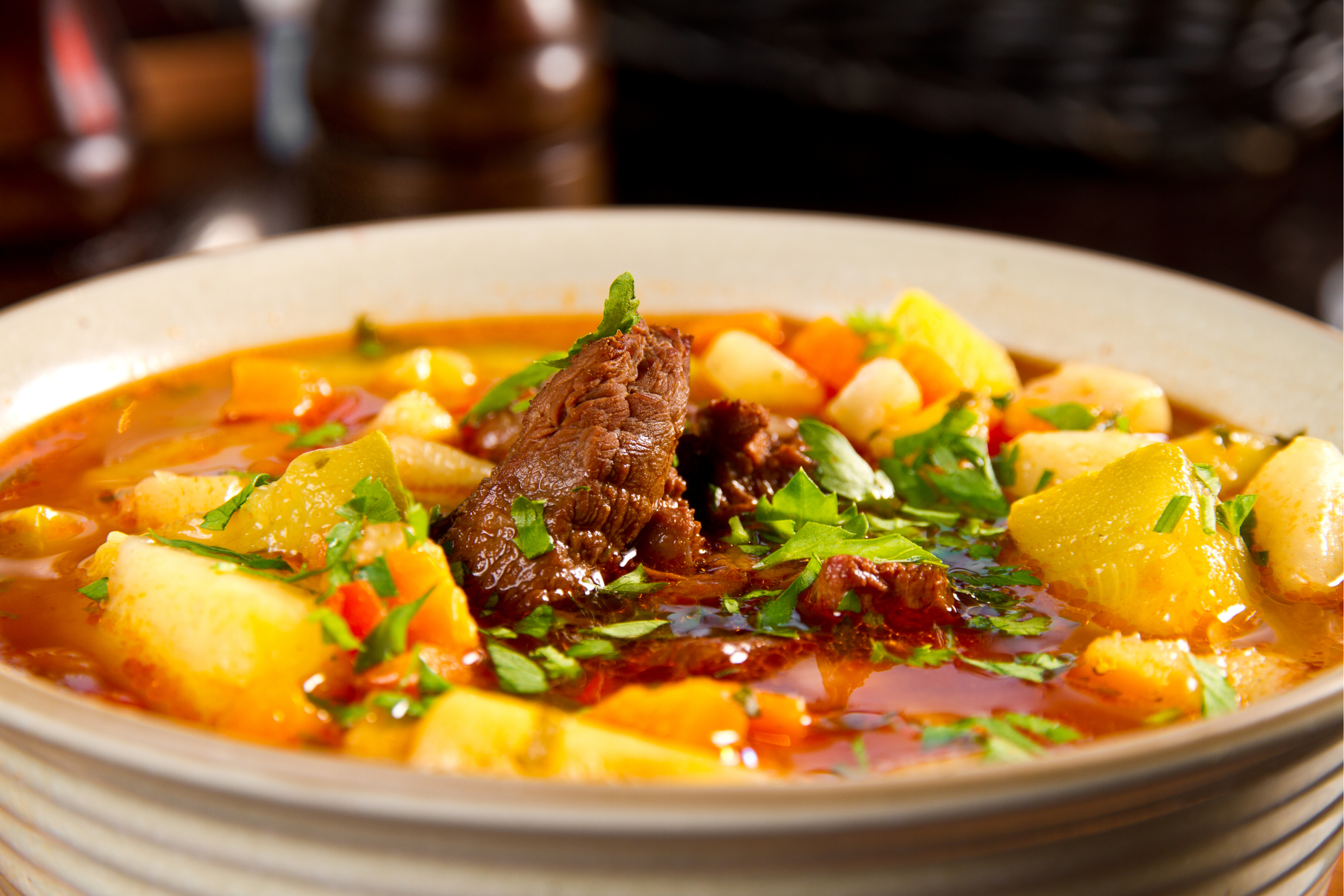 bowl of beef soup with potatoes, carrots, and parsley