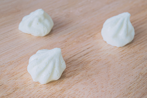 Scalloped meringue kisses on natural wood background