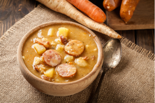 Wooden bowl of split pea and hot dog soup