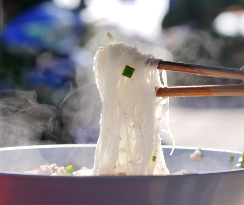 steaming rice noodles held over bowl with chop sticks